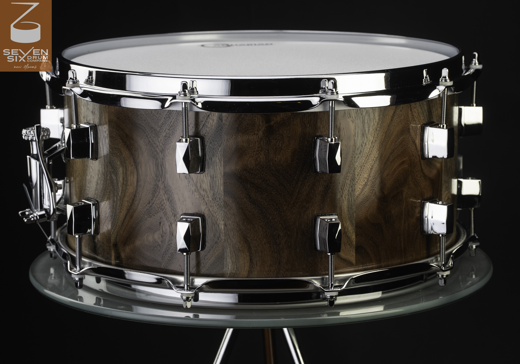 Handmade walnut snare drum with a natural wood finish, polished chrome hoops, lugs, and snare throw-off.