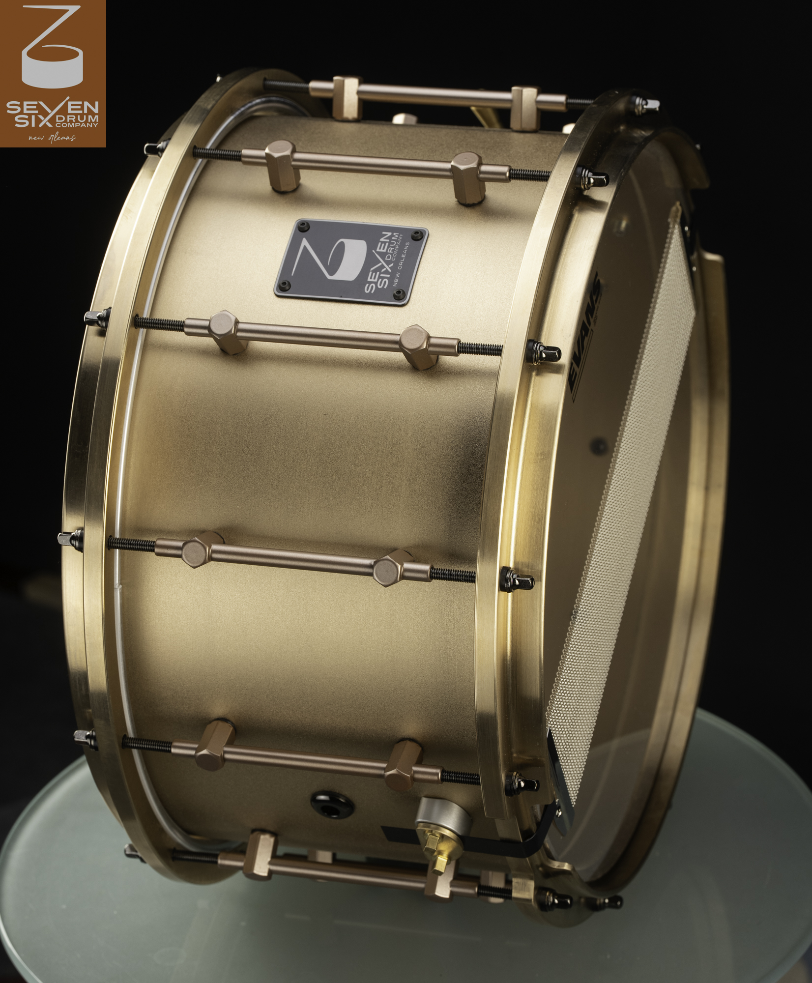 Satin bronze snare drum with matching cast hoops, copper-finished tube lugs, and black tension rods.