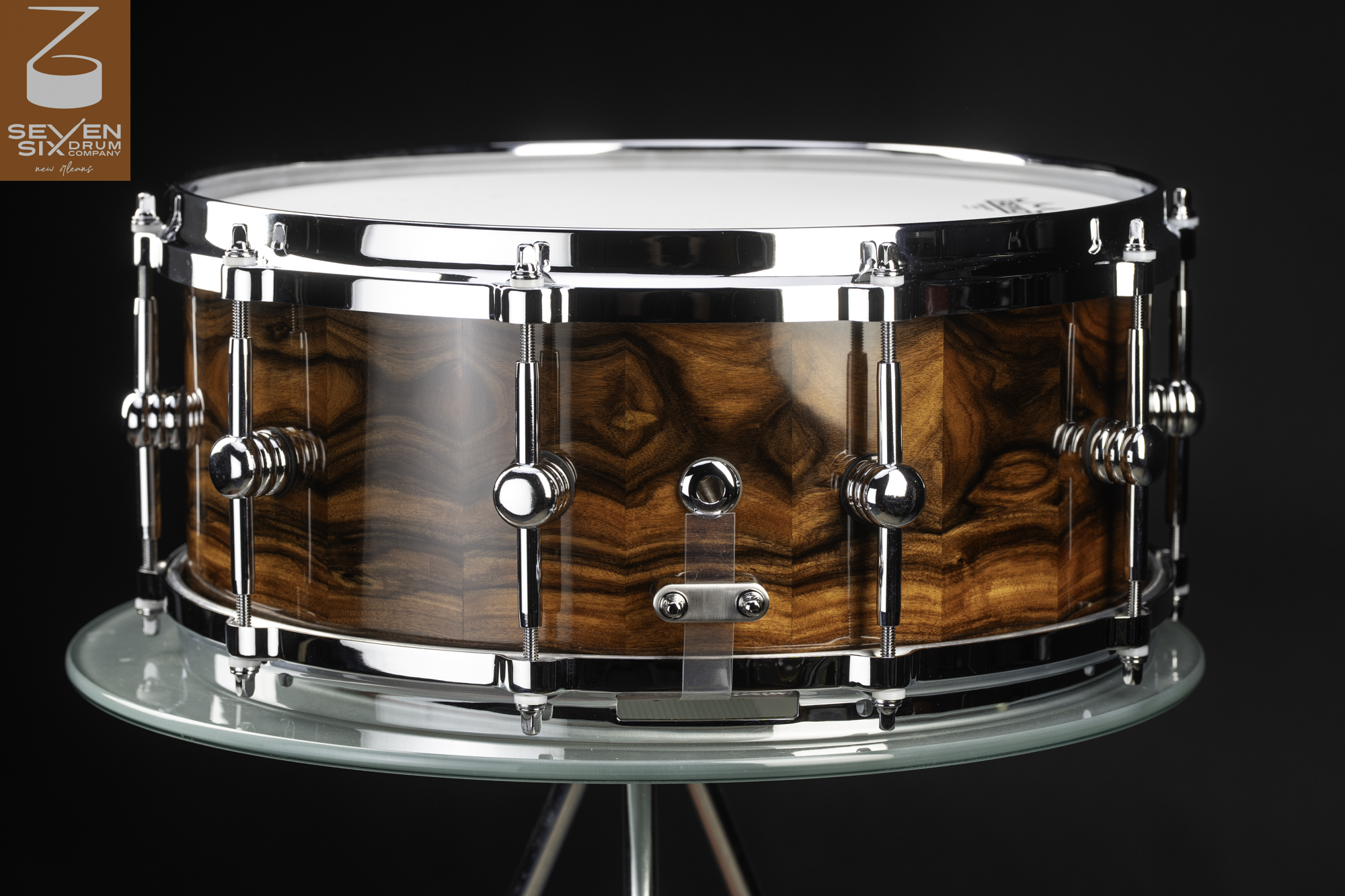 Handmade snare drum with a high-gloss figured wood shell, polished chrome hoops, and single-point chrome lugs.