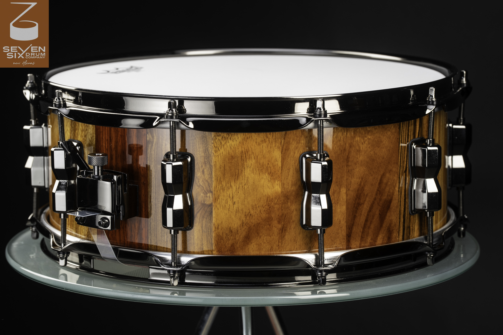 Handmade snare drum with a gloss natural wood shell, black nickel lugs, hoops, and a side-mounted throw-off.