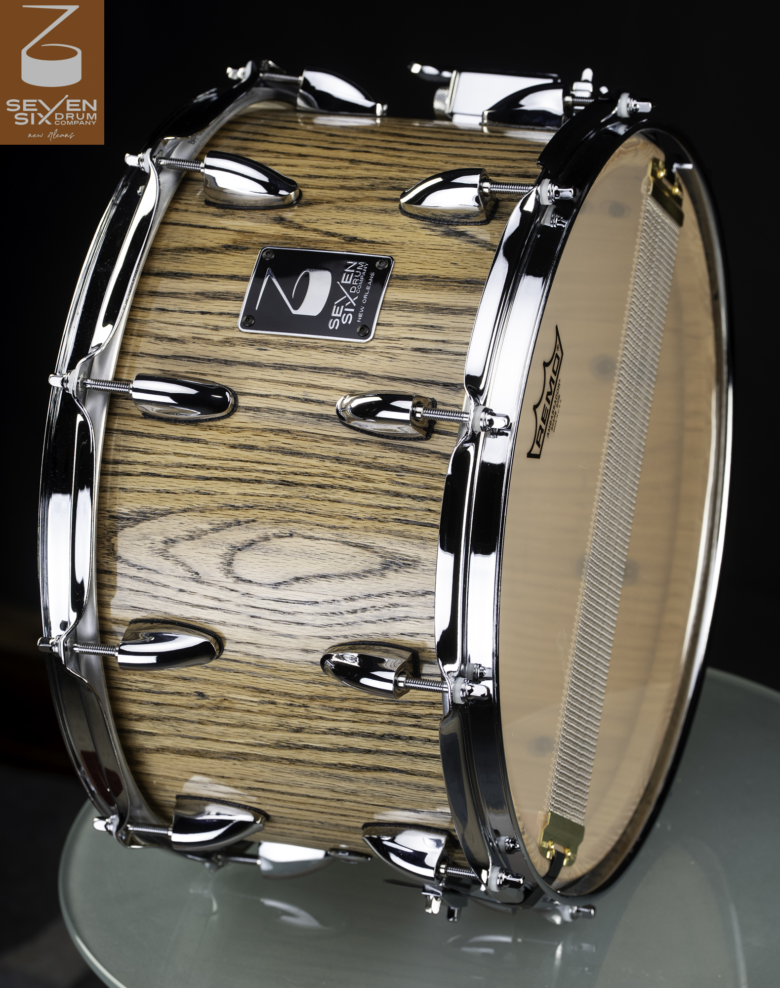 Handmade snare drum featuring a glossy natural wood grain shell with polished chrome lugs and hoops.