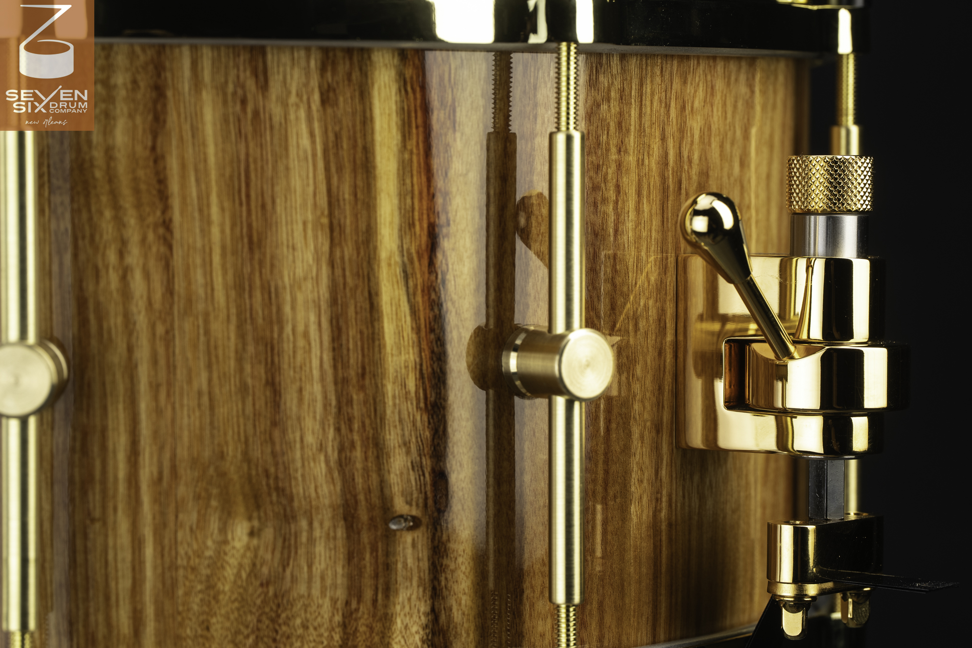 Handmade snare drum with a glossy natural wood shell, polished brass tube lugs, and a gold snare throw-off.