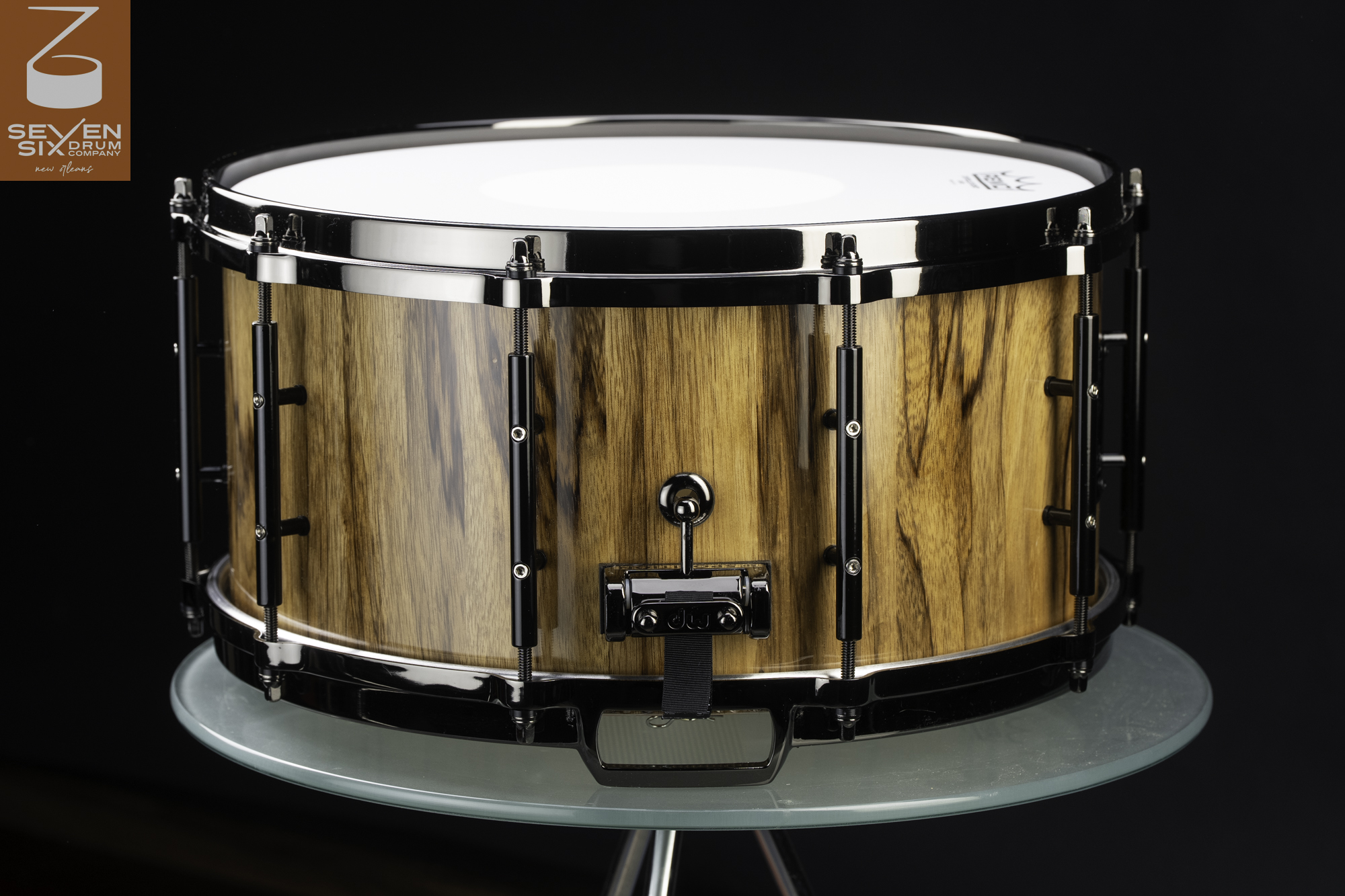 Handmade snare drum featuring a glossy wood grain finish and black nickel hardware with tube lugs.