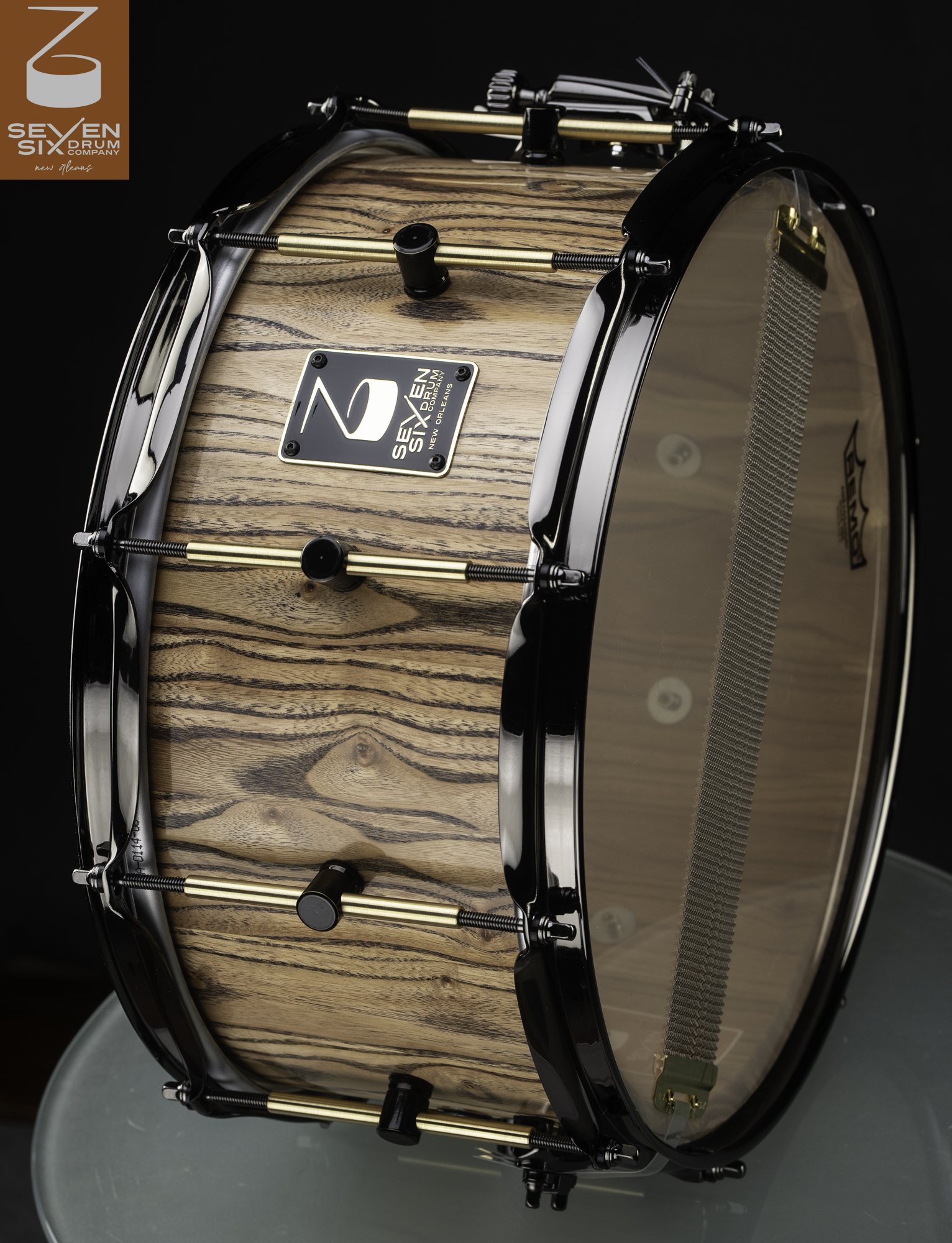 Handmade zebrawood snare drum with a natural finish, gloss black hoops, and brass tube lugs.
