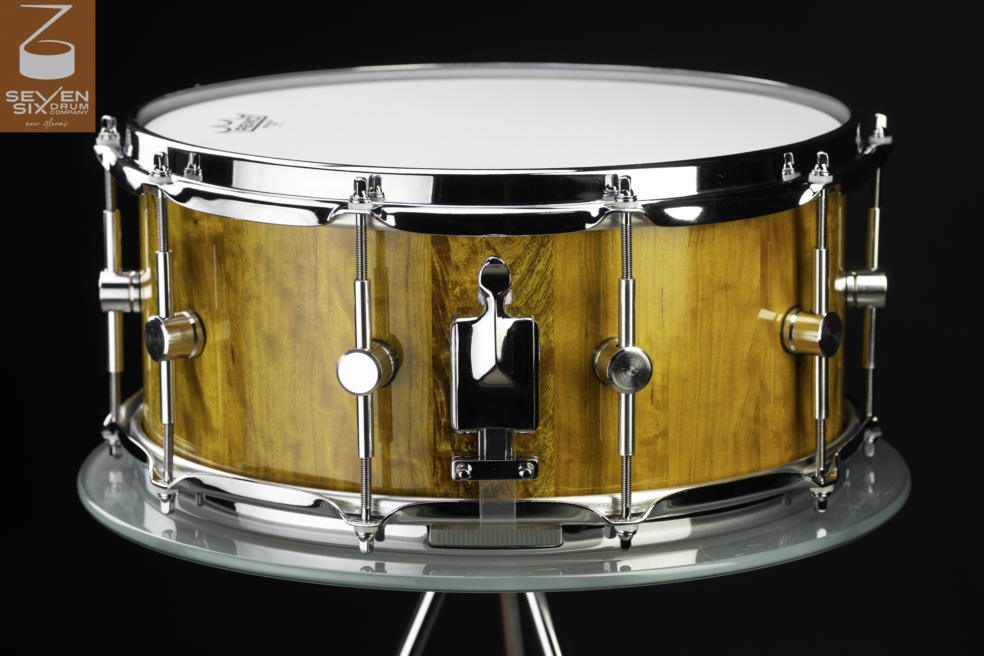 Handmade snare drum with a glossy golden wood shell, chrome hoops, round lugs, and a polished chrome throw-off.