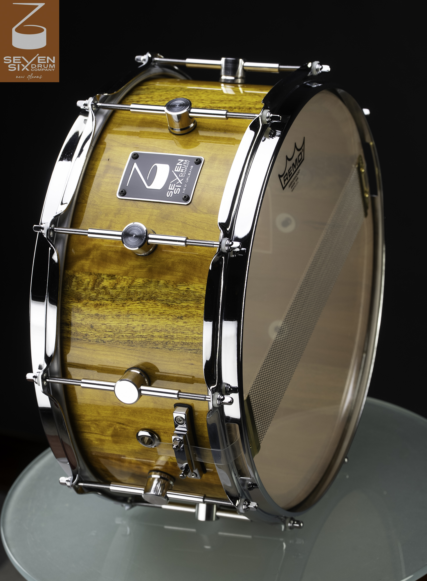 Handmade wooden snare drum with a high-gloss amber finish, chrome single-point lugs, and polished hoops.