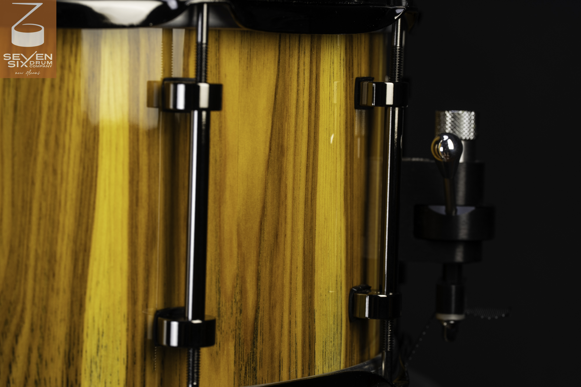 Handmade snare drum with a glossy yellow wood grain finish, black chrome tube lugs, and a snare throw-off.