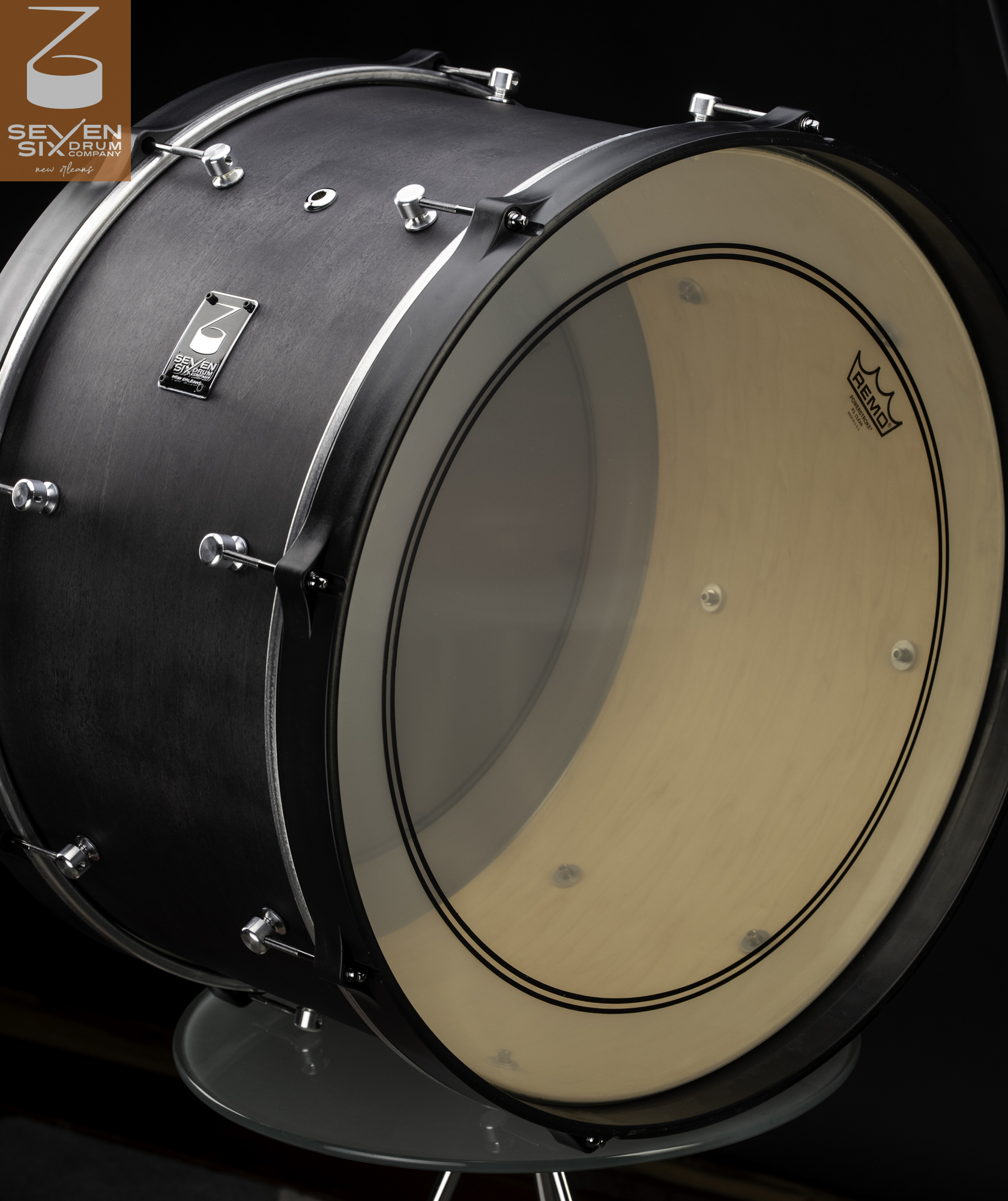 Bass drum with a matte black wood shell, natural interior, black hoops, and chrome lugs.
