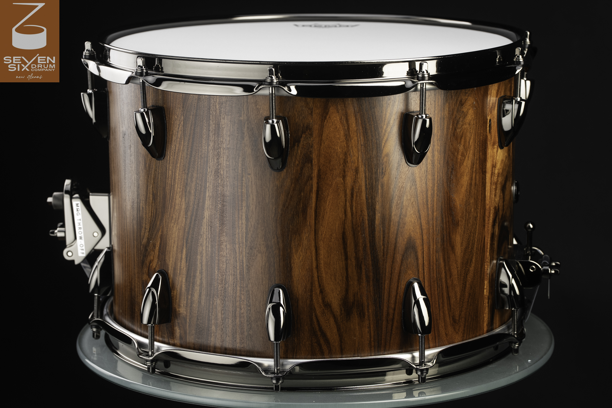 Deep wooden snare drum with a natural brown grain finish, polished black nickel hardware, and a MAG throw-off.