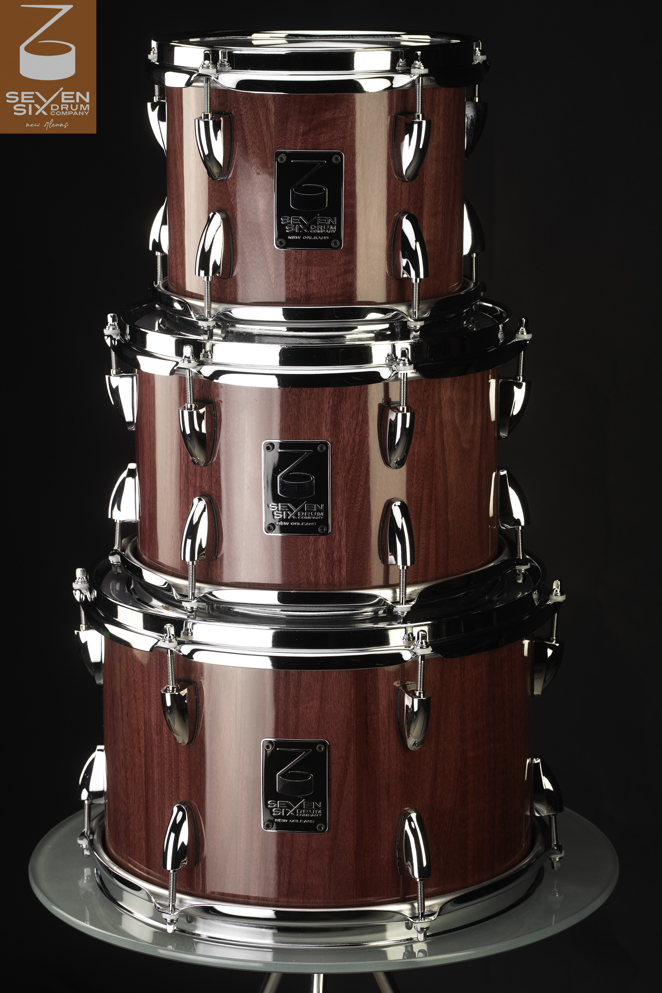 Three stacked drums with a glossy crimson wood finish, polished chrome hoops, and teardrop lugs.