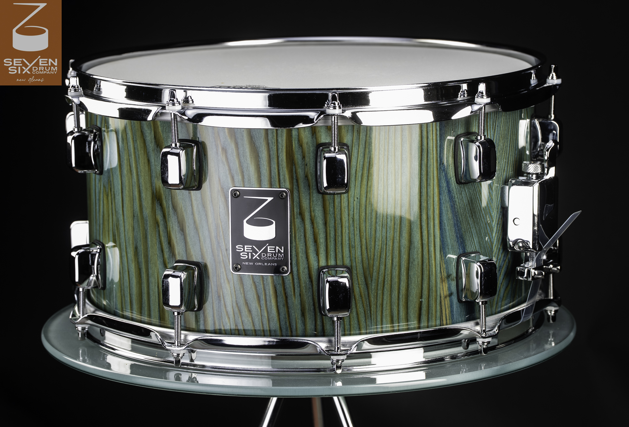 Handmade snare drum featuring a glossy teal-stained wood shell, chrome lugs, and polished chrome hoops.