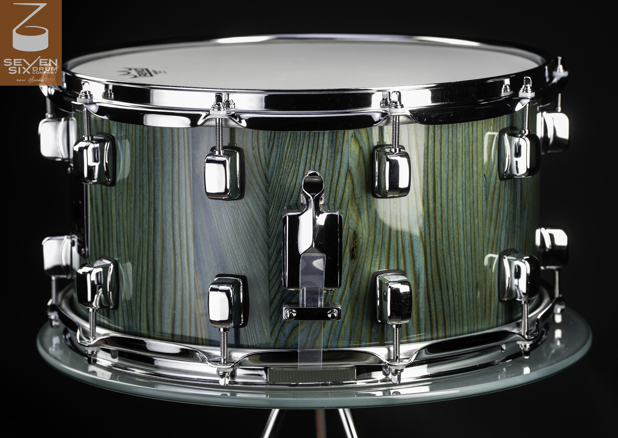 Handmade snare drum with a glossy teal-stained wood shell, chrome lugs, and a matching chrome snare throw-off.