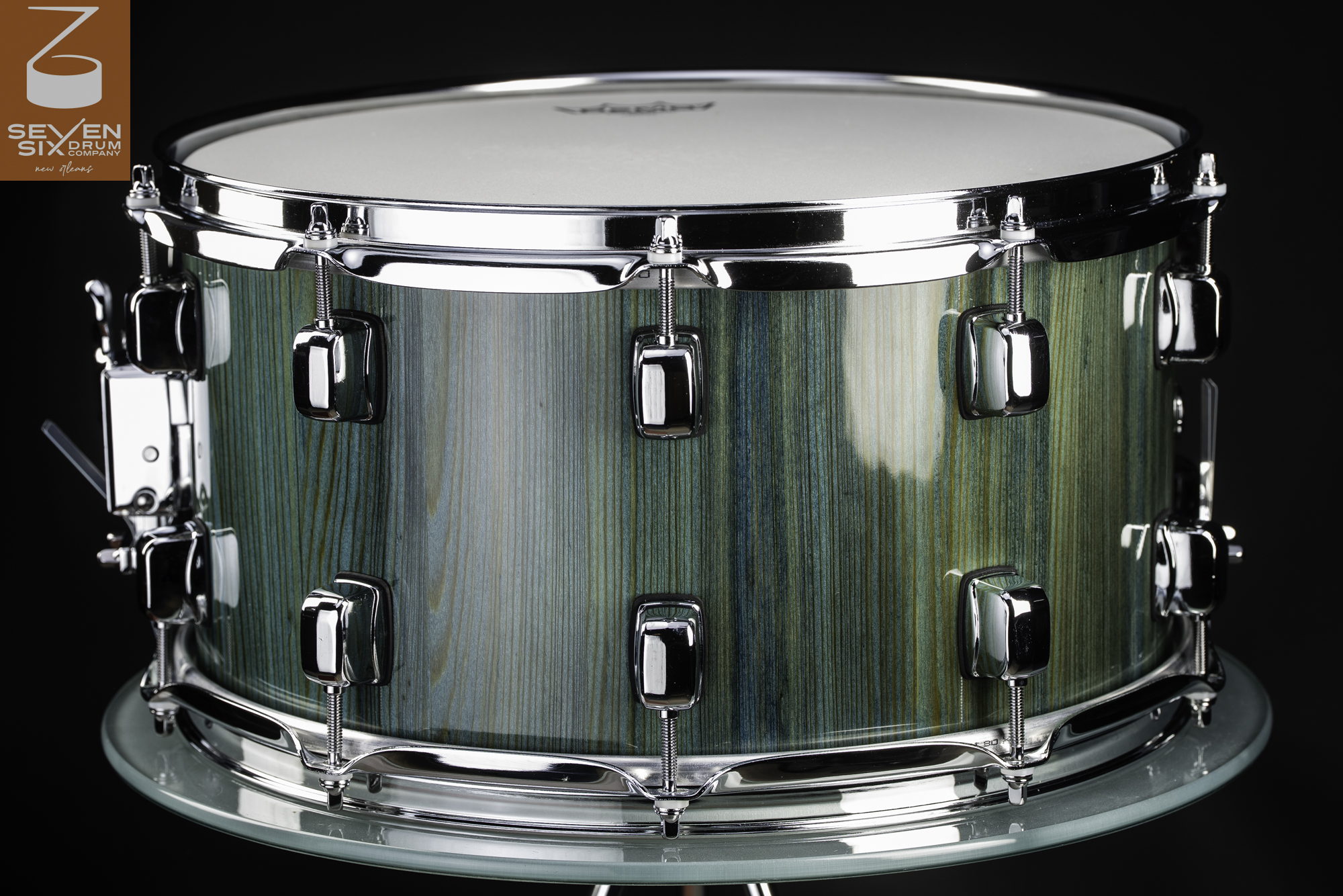 Snare drum featuring a glossy teal vertical-grain wood shell with polished chrome lugs and hoops.