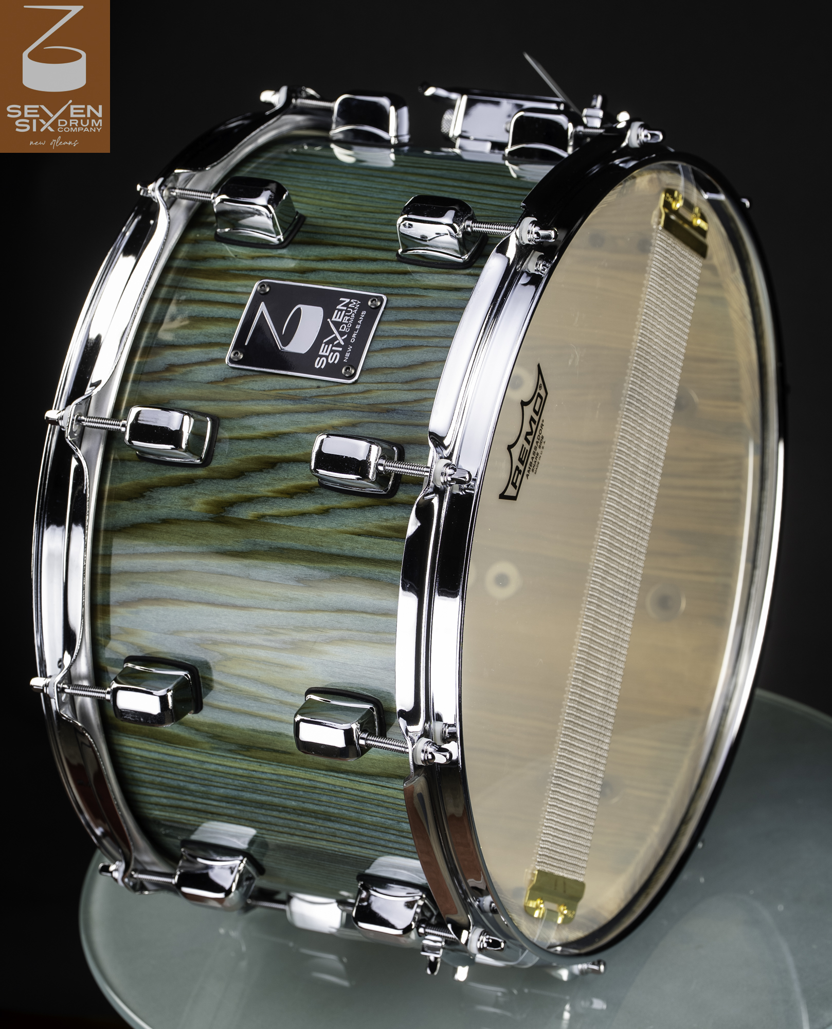 Handmade snare drum featuring a glossy teal-stained wood grain finish with polished chrome lugs and hoops.