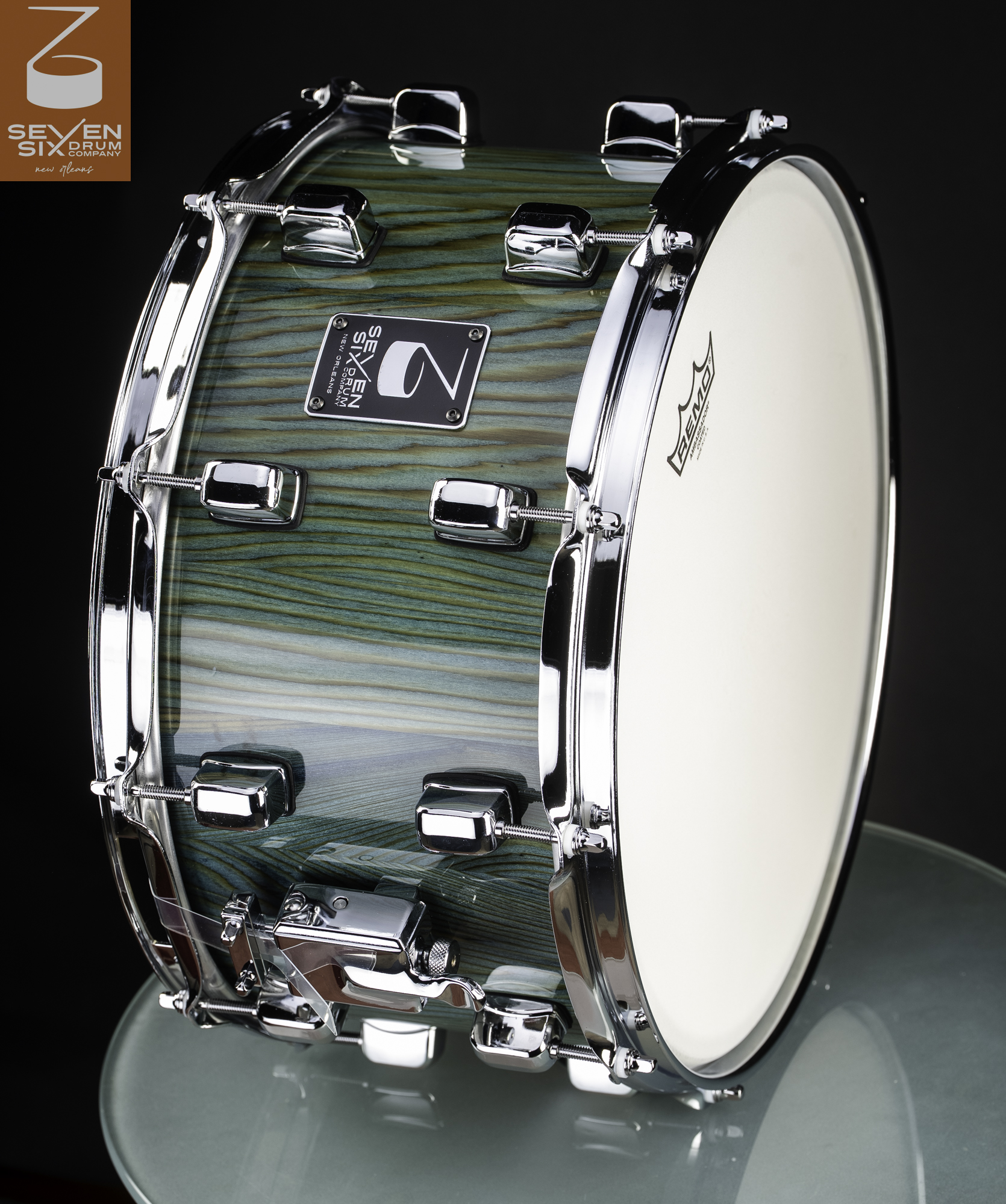 Handmade wood snare drum with a glossy teal-stained grain finish and polished chrome lugs, hoops, and throw-off.