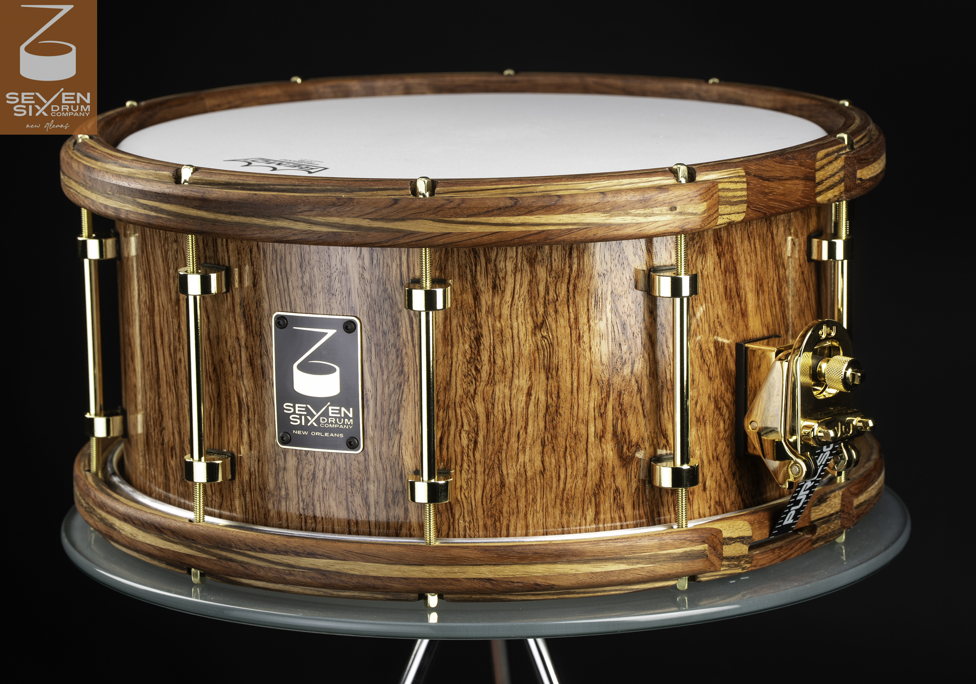 Glossy natural wood snare drum with matching wood hoops and polished gold tube lugs and throw-off.