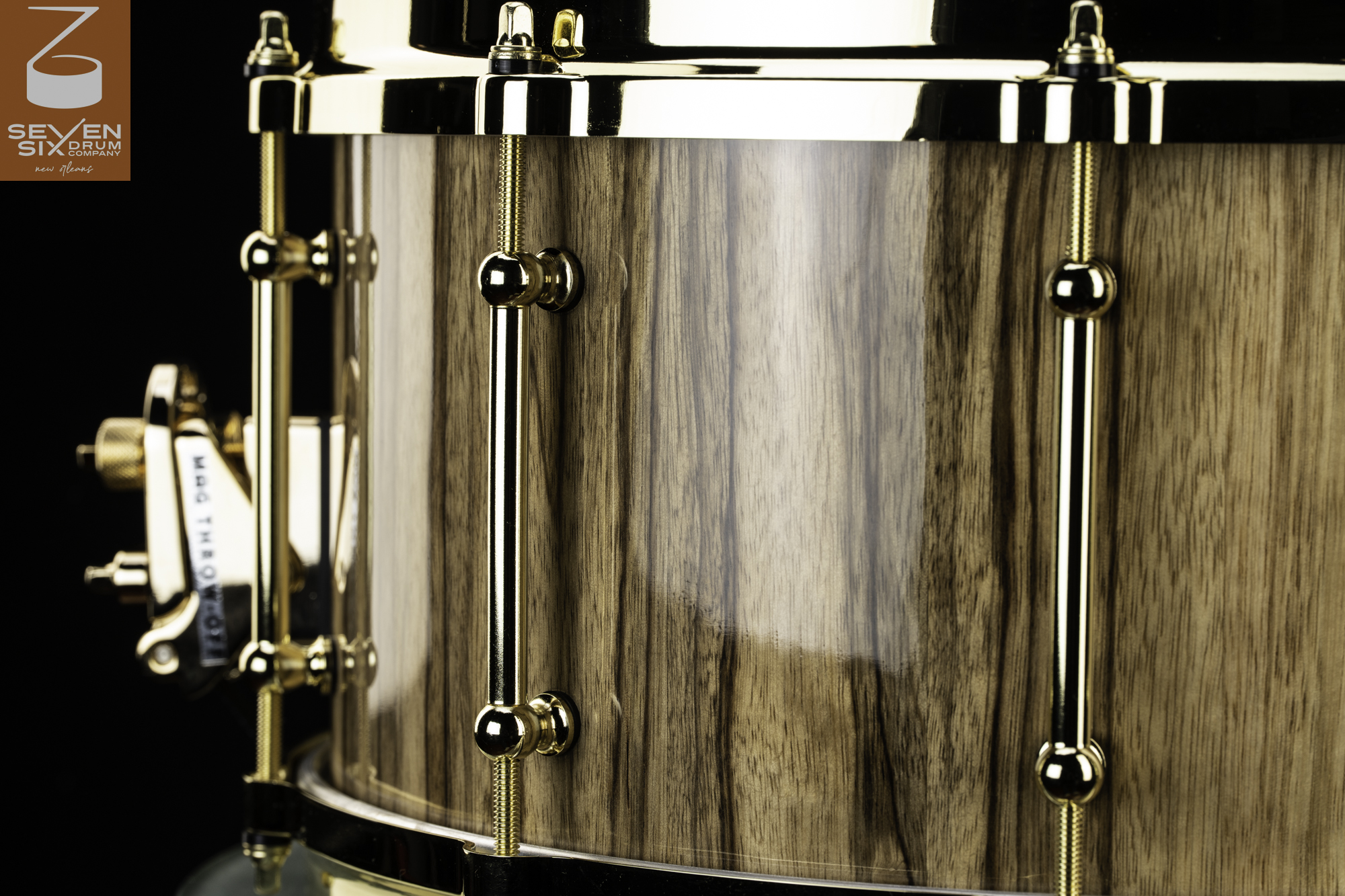 Snare drum with a high-gloss wood grain shell, polished gold tube lugs, hoop, and throw-off.